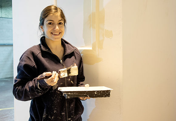 Apprentice smiling with paint tray and brush in hand