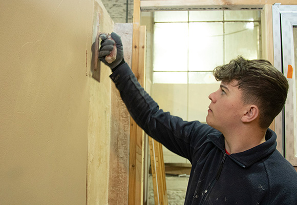 Apprentice plastering wall