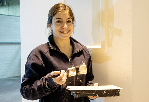 Jessica smiling with paint tray and brush in hand