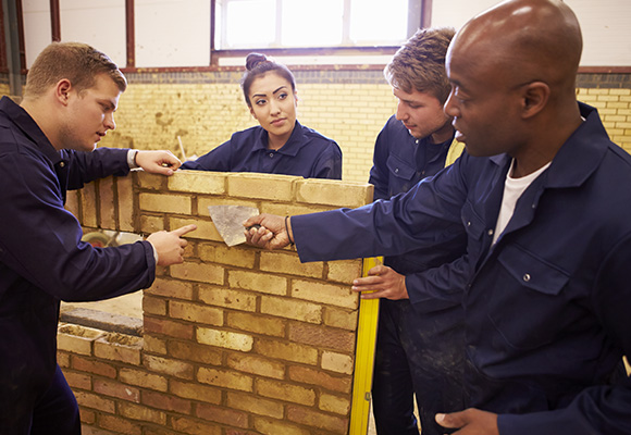 Bricklaying apprentices pointing a wall
