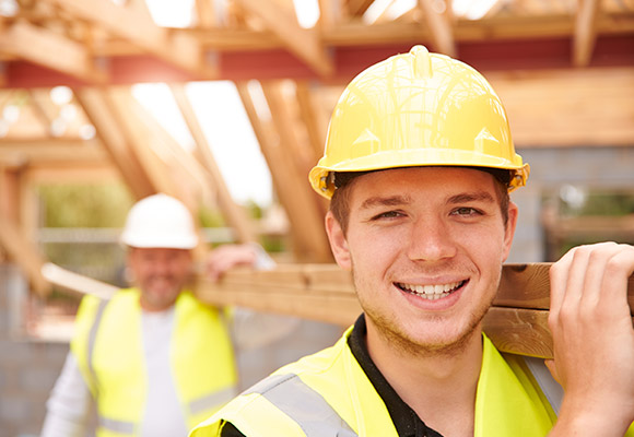 Carpentry apprentices and supervisor carrying joists