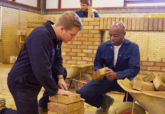 Apprentice and supervisor laying wall